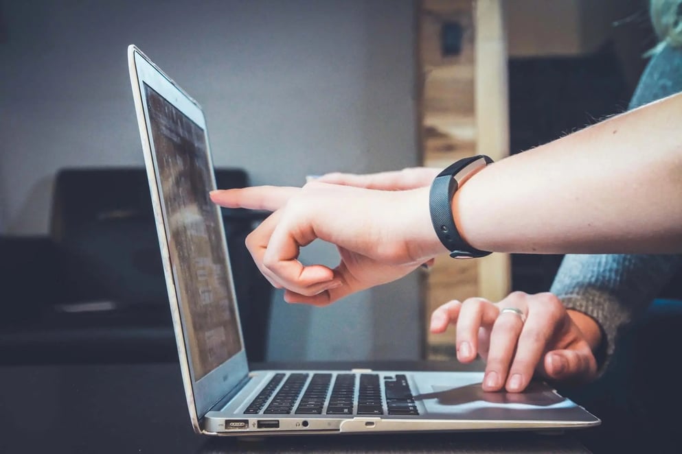 person pointing at laptop screen on desk
